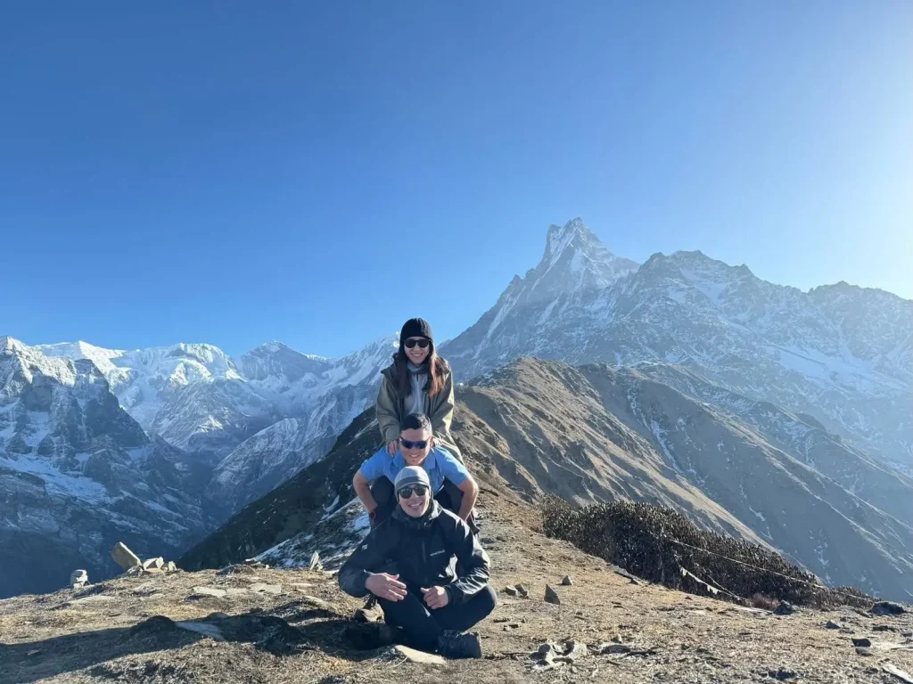Group of happy trekkers posing on a mountain ridge with snow-capped peaks during the mardi himal tre