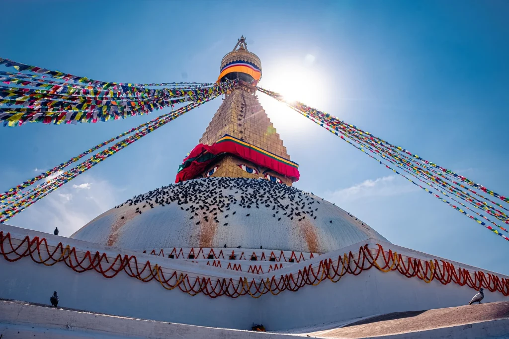 Majestic white dome of Boudhanath Stupa adorned with prayer flags under a bright sunny sky in the Kathmandu Valley.
