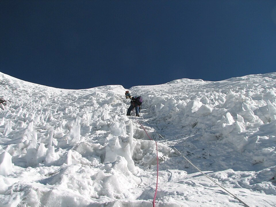 Island Peak Climbing features mountaineers navigating a steep, snowy slope using fixed ropes and alpine gear on Imja Tse.