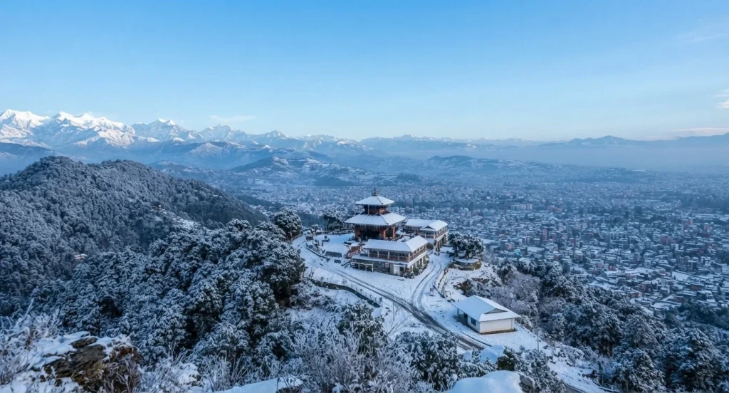 An aerial view of Chandragiri Hills and the surrounding landscape covered in fresh snow following a winter snowfall.