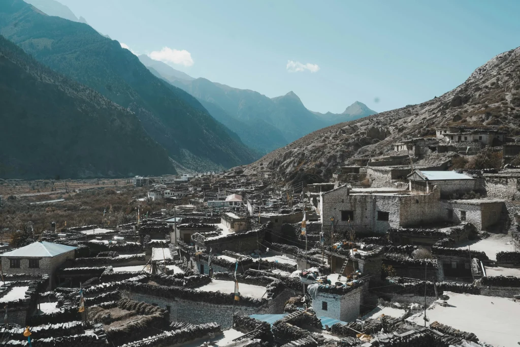 An elevated view of the traditional stone houses and flat roofs of Marpha village set against steep mountain ridges along the Annapurna Circuit.