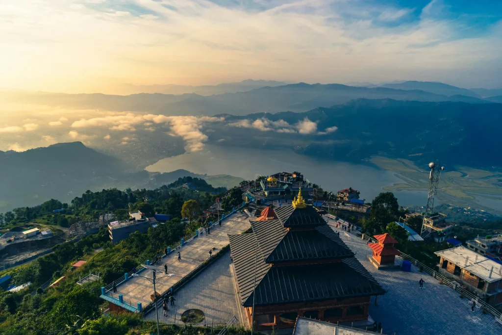 Sunrise view from Sarangkot temple overlooking Pokhara valley, low clouds, and Phewa Lake.