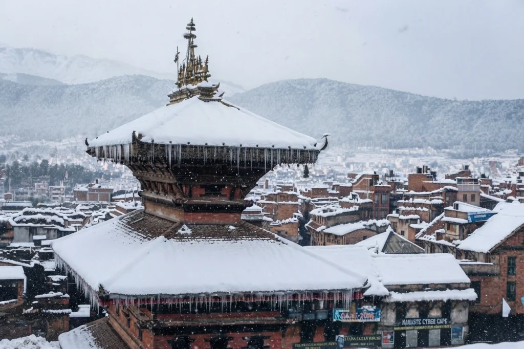 A close-up view of a traditional tiered temple roof and icicles overlooking a city during a winter snowfall.