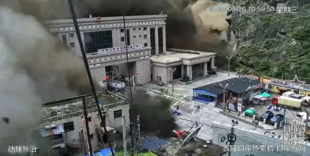 CCTV footage capturing a massive wall of dark brown dust and debris rolling down a mountain valley and completely engulfing the inspection buildings at the Gyirong Port along the China–Nepal border.