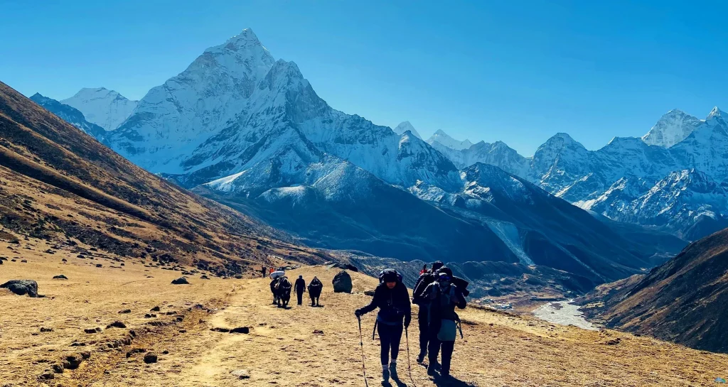 Trekkers walking along a wide high-altitude trail with Ama Dablam in the background during a standard vs luxury ebc trek.