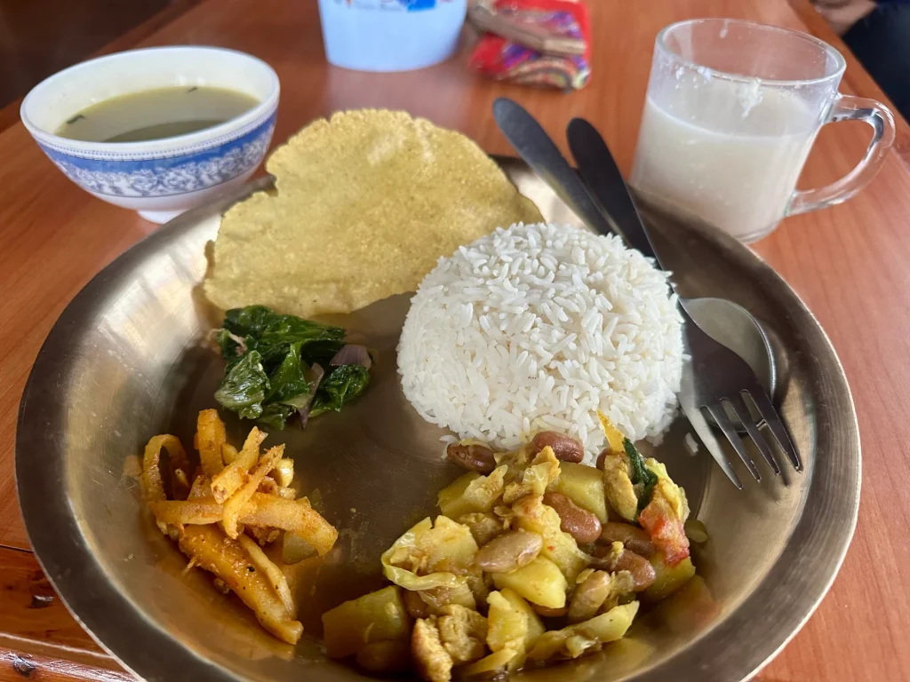 Authentic Nepali Dal Bhat food served on a traditional brass plate with rice, lentil soup, vegetables, and pickles.
