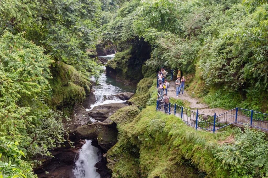 Visitors walking along the railed viewpoint path near Devi's Fall waterfall in Pokhara.
