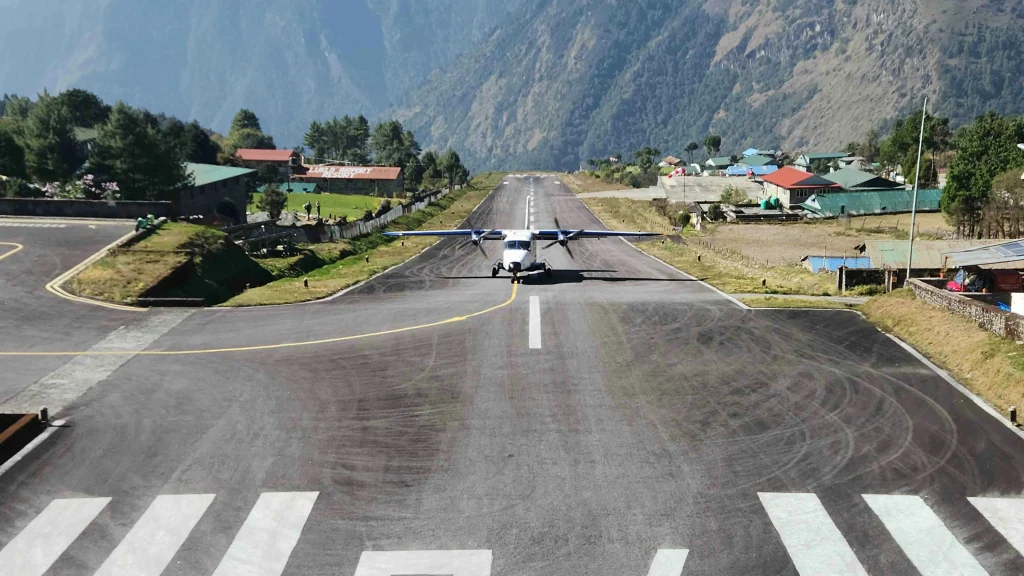 A small propeller plane parked on the inclined runway at Tenzing-Hillary Airport in Lukla, the main starting point for the everest base camp trek.