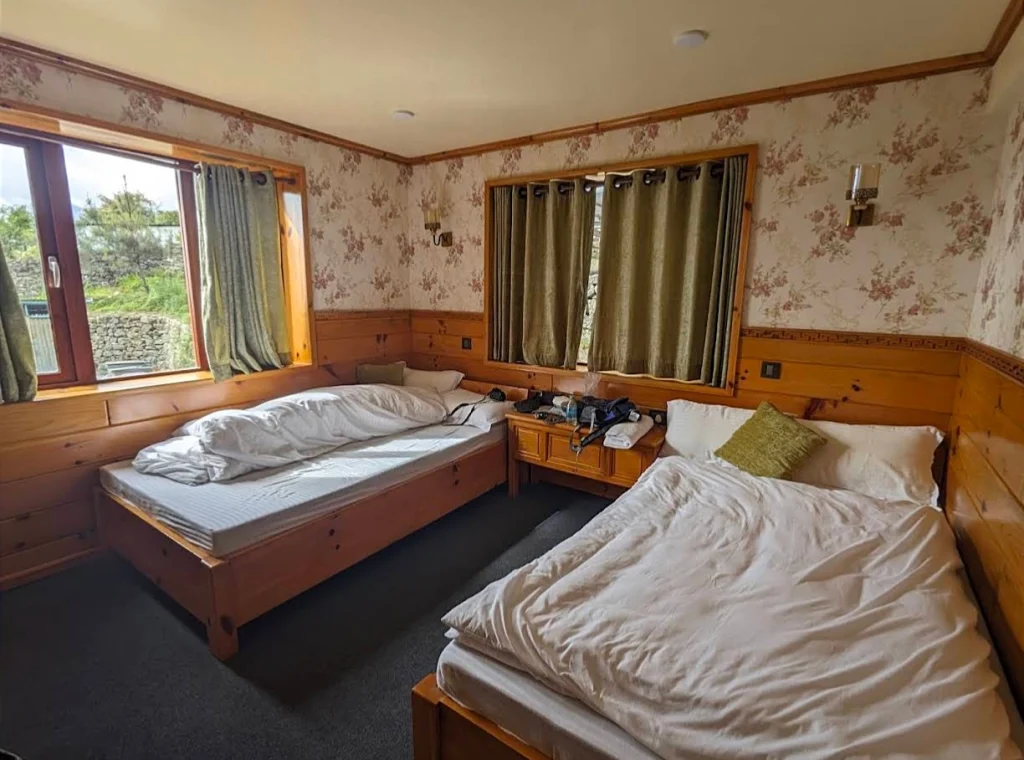 A cozy, wood-paneled bedroom inside a premium teahouse lodge, highlighting comfortable accommodations on a standard vs luxury ebc trek.