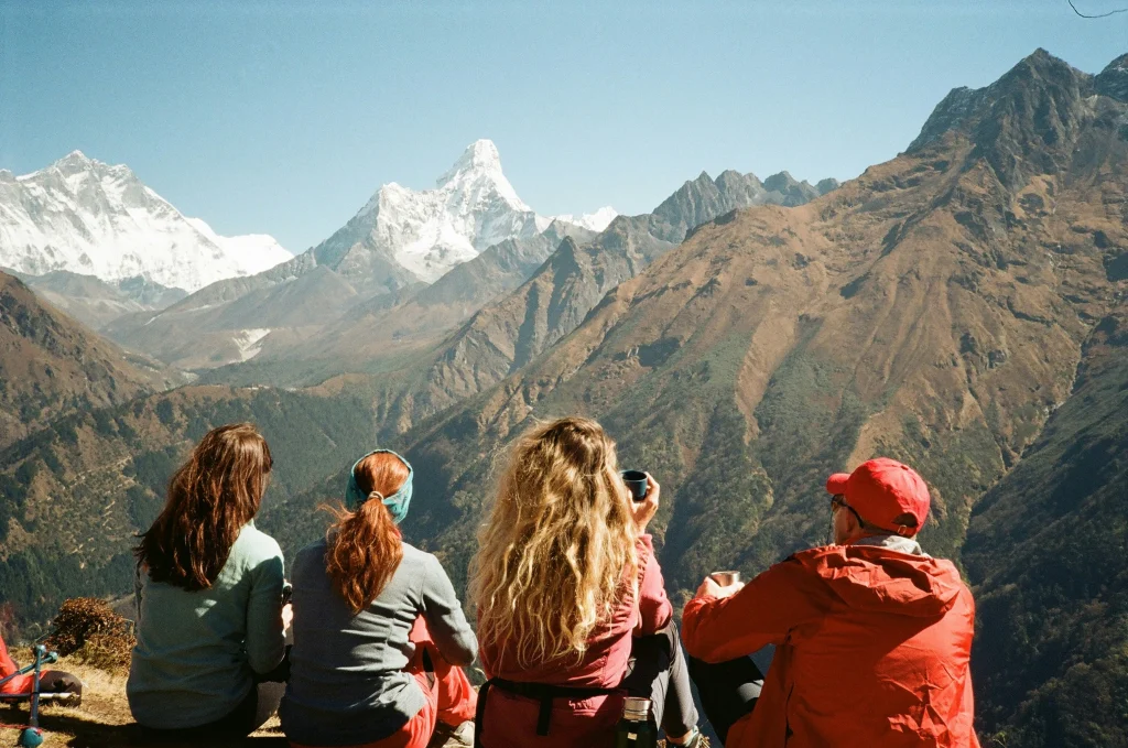 A group of four trekkers taking a breaks and admiring the Himalayas, an important element in both a standard vs luxury ebc trek.
