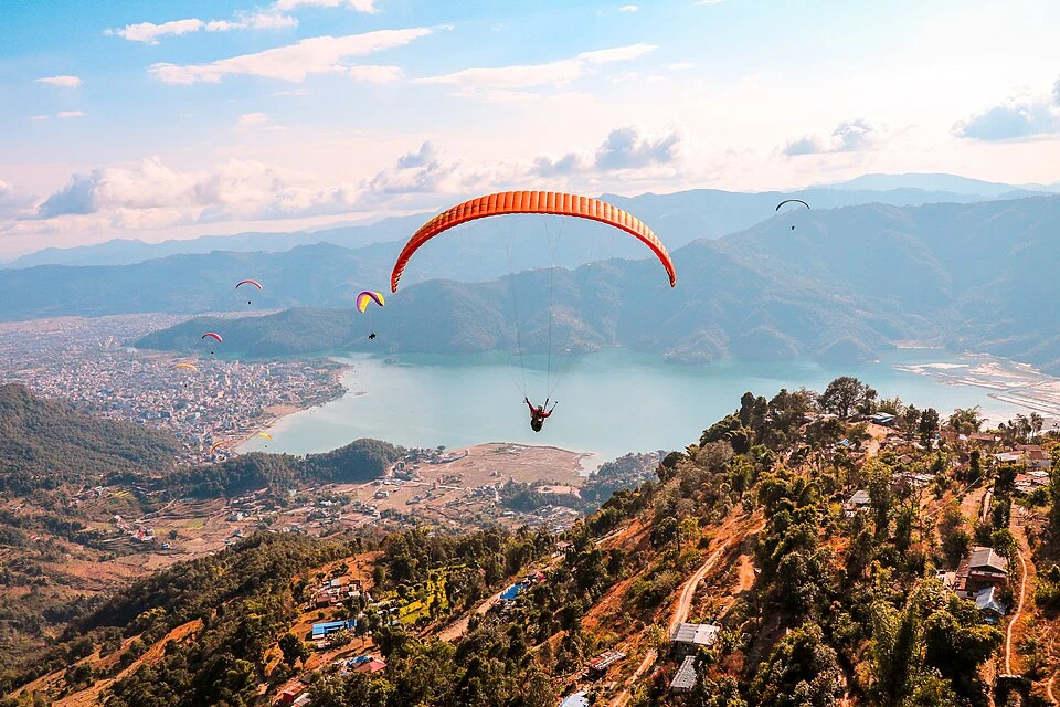 Paragliders flying high above the hills, city, and Phewa Lake in Pokhara